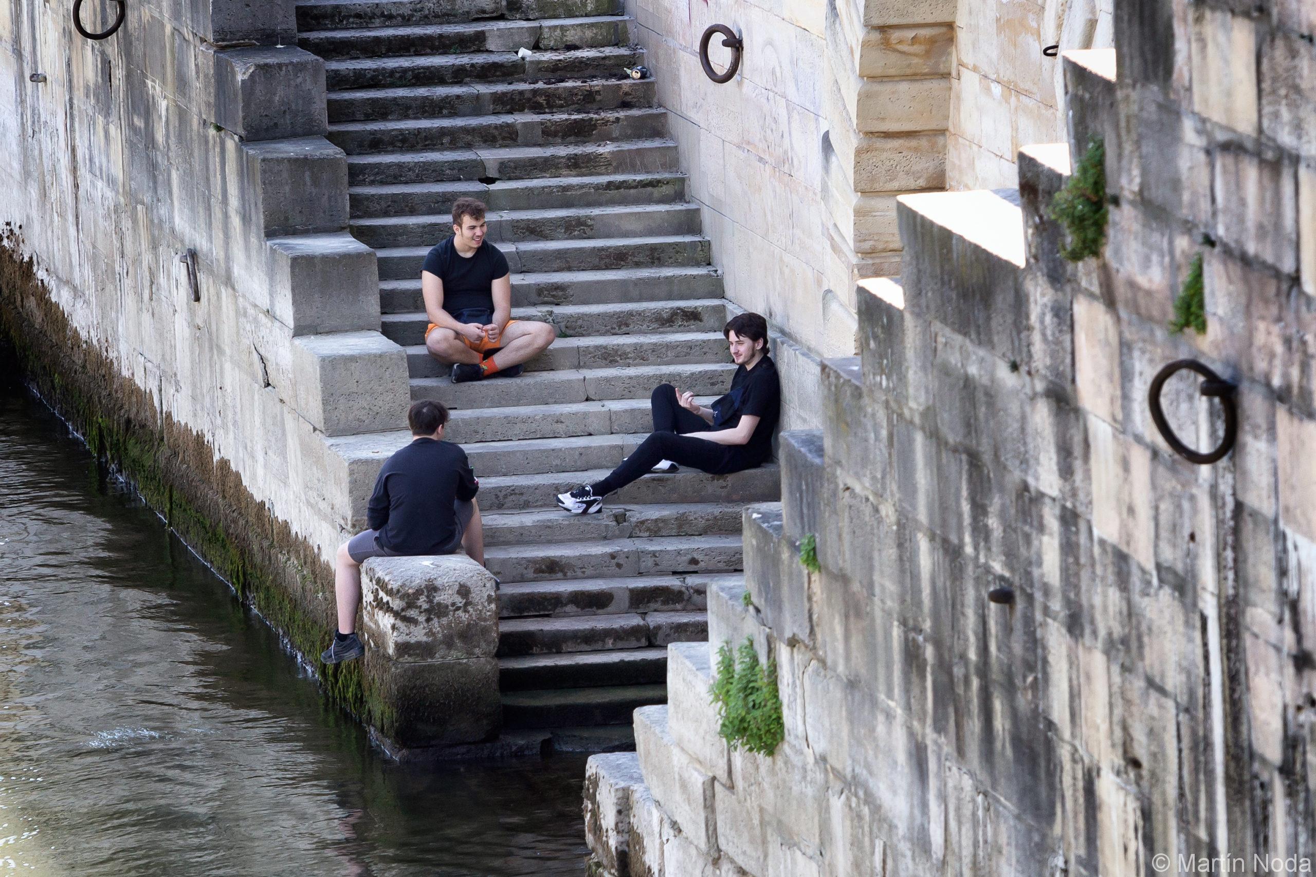 Trois jeunes discutent sur les bords de la Seine en se tenant a une distance de sécurité, Paris, 20 mai 2020.
